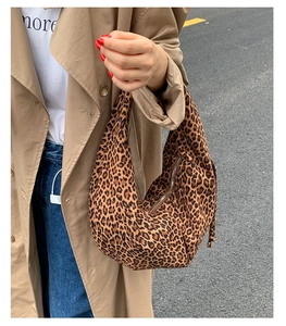 Close-up of leopard print canvas crescent bag styled with an autumn trench coat