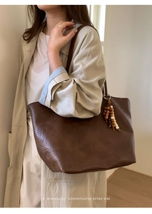 Close-up of deep brown tote bag with leather texture and retro beaded charm accessory