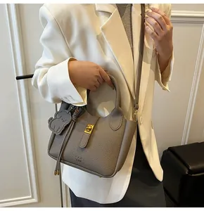 Close-up of grey litchi texture leather bucket bag with metal lock and cute dog charm