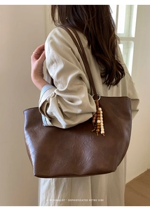 Deep brown minimalist tote bag detail featuring wooden bead tassel on retro shoulder bag