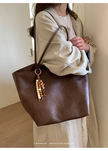 Detailed view of dark brown retro tote bag with textured faux leather and beaded tassel charm