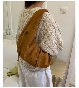 Close-up of brown suede dumpling bag worn on shoulder with soft draped texture