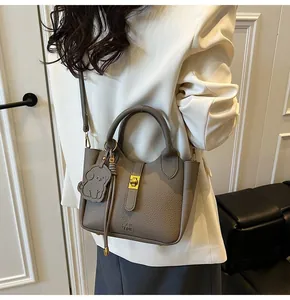 Close-up of grey litchi texture bucket bag with gold clasp and puppy pendant
