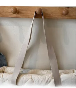 Detail of soft beige quilted tote bag showing the wide webbing handle and diamond pattern