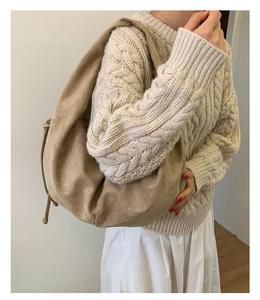 Detail view of large beige suede hobo bag with side drawstring worn by model in knitwear