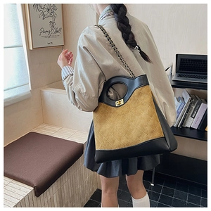 Detail of quilted brown suede tote bag with black leather trim and gold chain strap