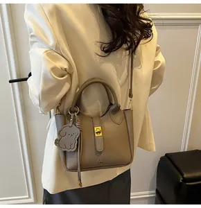 Detail of lychee pattern leather bucket bag in taupe with gold twist lock and dog charm