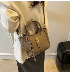 Brown lychee leather bucket bag with gold hardware and a cute dog charm detail