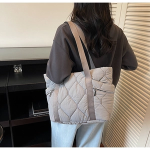 Detailed view of grey quilted tote bag featuring symmetric zipper pockets and nylon straps
