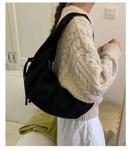 Detailed side view of the black oversized suede dumpling bag with drawstring details