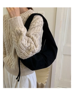 Detail of black faux suede crescent bag worn by model over a beige sweater