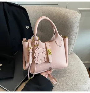 Detail of pink lychee leather bucket bag with gold clasp and cute bear charm pendant