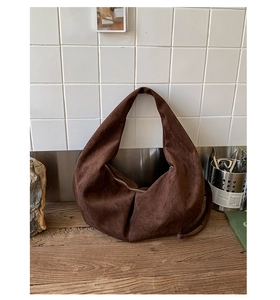 Detail of soft brown suede hobo bag texture with elegant metallic zipper closure