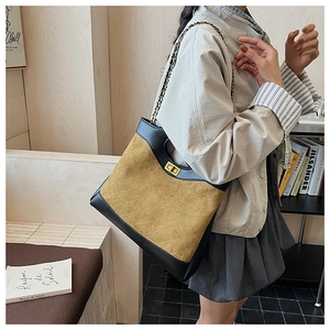 Detail of a quilted ginger suede handbag with chain strap and gold twist lock closure