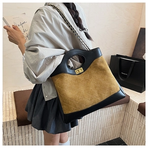 Detailed view of yellow quilted suede bag with black leather edges and metal chain strap