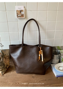 Close-up of deep brown tote bag with premium faux leather texture and beaded tassel