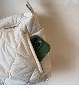 Detail of quilted puffer tote bag side pocket with smartphone storage functionality