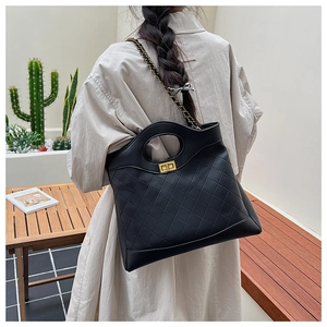 Quilted black leather bag with gold chain strap shown on a model in beige coat