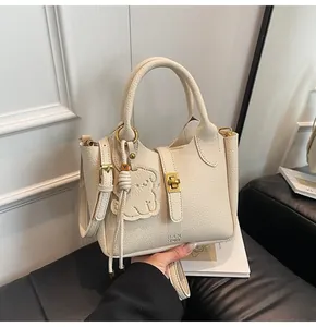 Detailed macro of cream lychee texture leather handbag with golden lock and bear charm