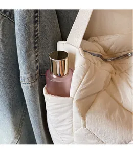 Detail of white quilted tote bag featuring a side pocket for convenient storage