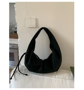 Detailed close-up of large black crescent shoulder bag with drawstring detail and zipper