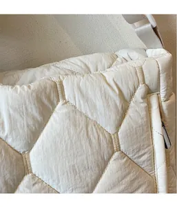 Detail of quilted hexagonal pattern on lightweight beige nylon tote bag for women