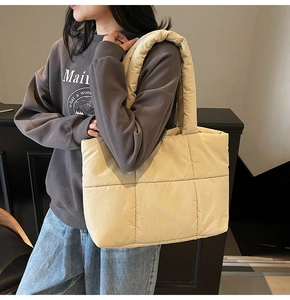 Dettaglio della borsa tote in velluto trapuntato beige con tracolla imbottita sul modello