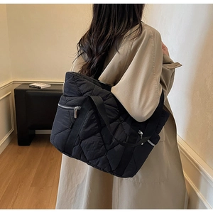 Detail of black quilted puffer tote bag with silver zipper and large diamond pattern