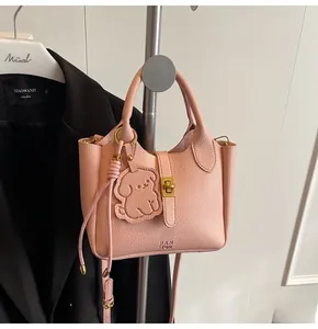 Detailed view of pink lychee grain bucket bag with dog pendant and golden lock
