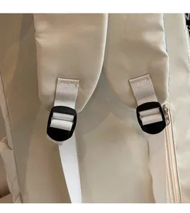 Detail of adjustable wide shoulder straps and plastic buckle on cream padded backpack