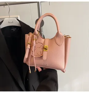 Close-up of pink litchi texture leather handbag with gold clasp and bear charm