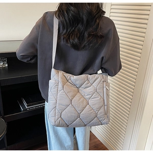 Detail of grey quilted crossbody bag with side zipper pocket and wide fabric strap