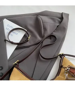 Détail du sac à bandoulière en daim jaune avec garniture en cuir brun et pendentif ressort