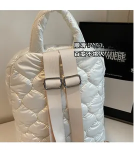 Close-up of beige quilted backpack showing adjustable straps and silver metal buckles