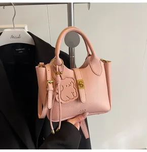 Close-up of pink litchi grain leather handbag with gold twist lock and cute bear charm