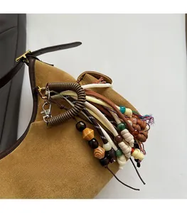 Détail d'un bijou de sac décoratif avec perles et cordon sur un sac à main en daim marron
