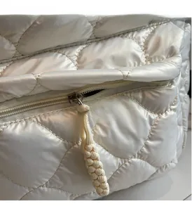 Detailed close-up of smooth metal zipper and white woven puller on quilted puffer backpack