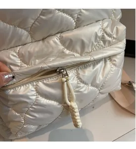 Close-up of white quilted fabric backpack with woven cord zipper puller detail