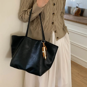 Minimalist black large tote bag with wooden bead tassel shown in a lifestyle daily setting