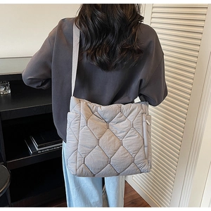 Detail of grey quilted nylon tote bag with wide adjustable strap and large diamond pattern
