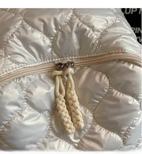 Detail of white quilted space cotton backpack with dual zippers and woven cord pulls