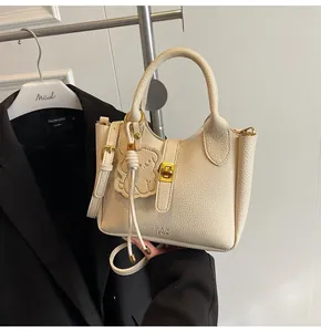 Detailed macro view of cream litchi texture leather bucket bag with gold metal lock