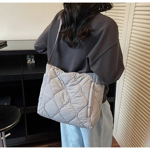 Detail view of light grey quilted tote bag with side hidden zipper and minimalist strap