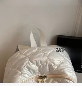 Detail of pearl white quilted nylon backpack with reinforced top handle and double zippers