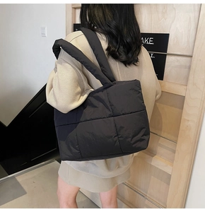 Dettaglio di una grande borsa tote trapuntata nera in nylon morbido su una modella