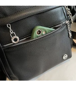 Detail of lychee pattern leather backpack featuring a zip pocket and silver chain