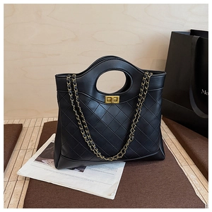 Detail of black quilted leather handbag with gold chain strap and metal twist lock