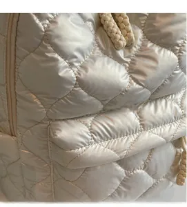 Close-up of quilted champagne puffer fabric with metallic finish and braided rope detail