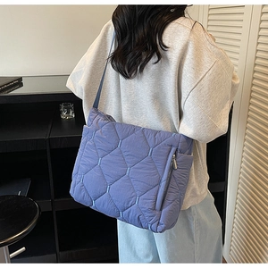 Detail of purple quilted tote bag showing hexagonal stitching and blue contrast thread
