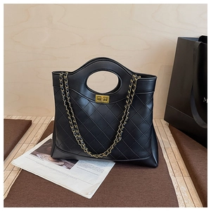 Detail of black quilted leather tote with round handle and golden chain strap